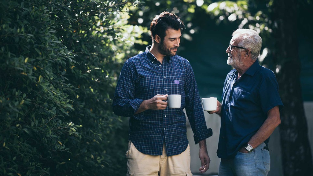 Two adults walking in the garden with a coffee and chatting